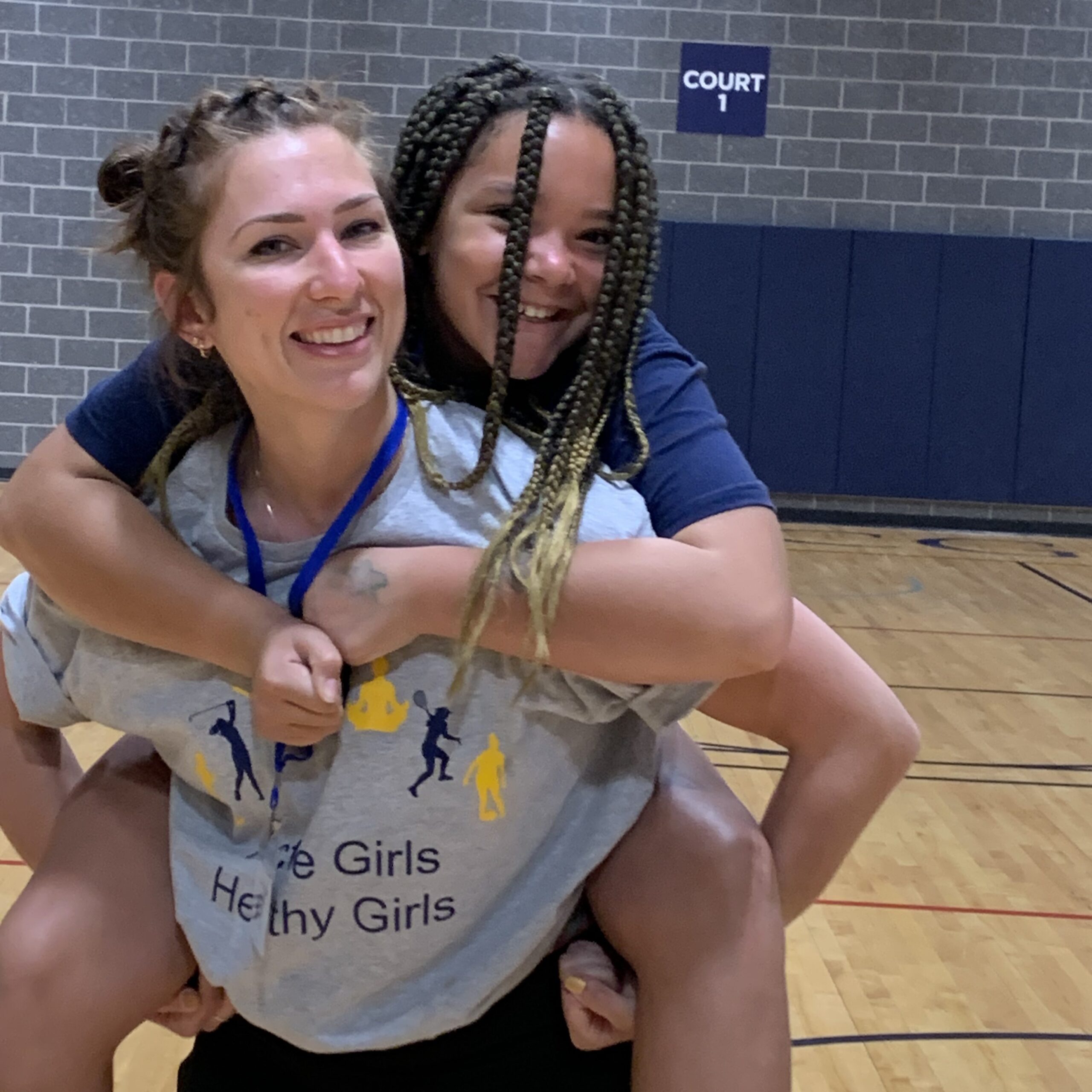 Wellness Warrior counselor gives a camper a piggyback ride