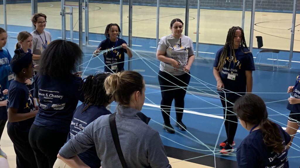 Campers do the web of support activity in a circle with a ball of yarn