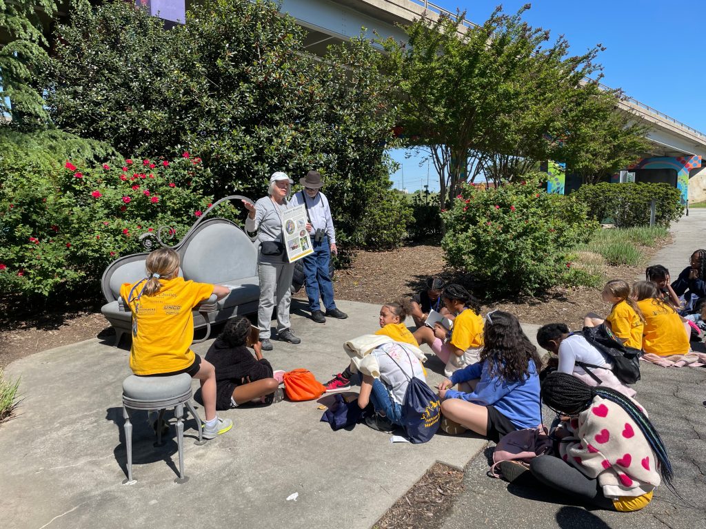 Campers sitting in the Greenway listening to bird watching instructors.